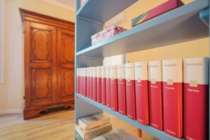 A bookshelf with red and white books, a wooden cabinet, and a blue shelf. - Levante Collection (Bologna)