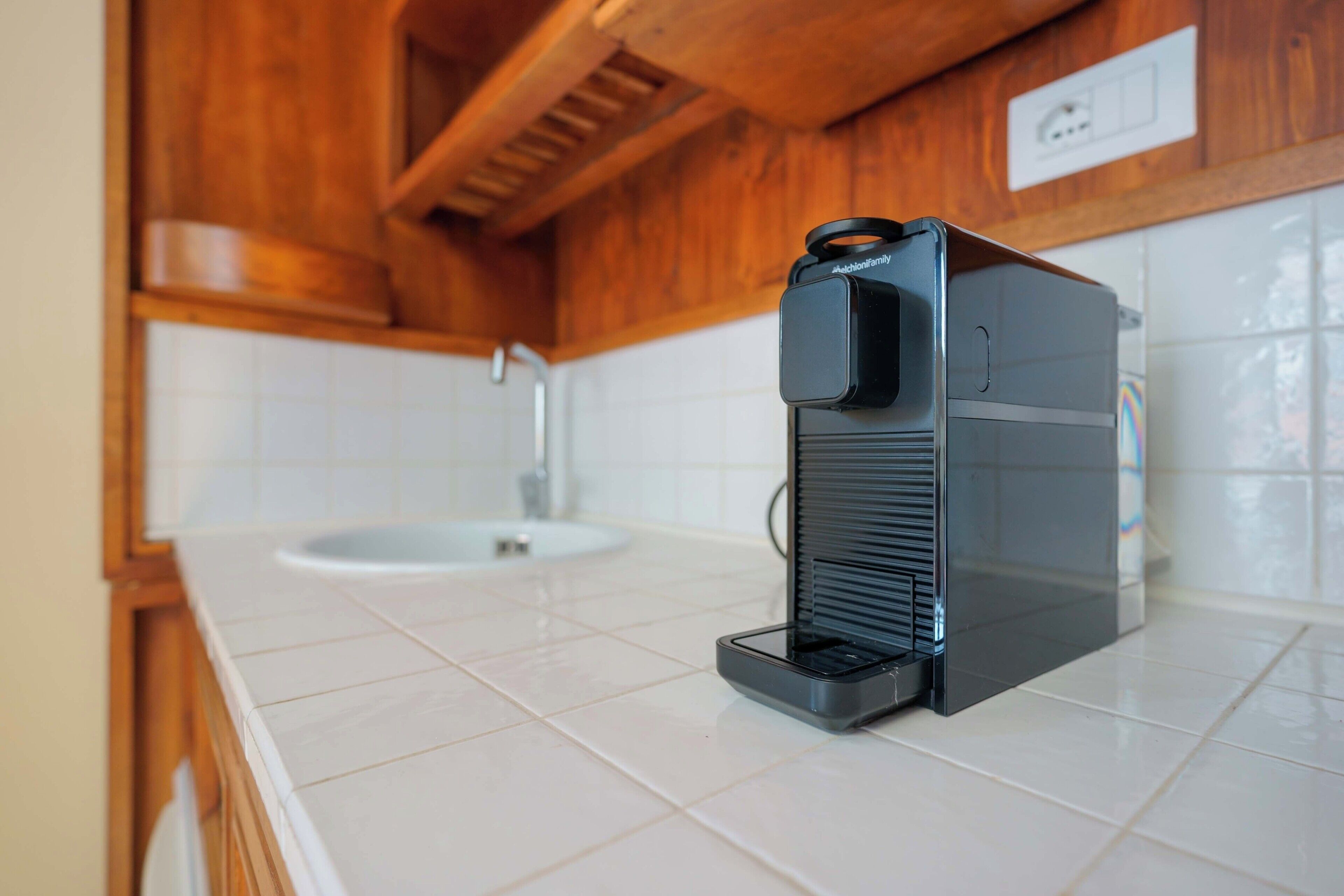 A kitchen with a coffee maker, a sink, and wooden cabinets.