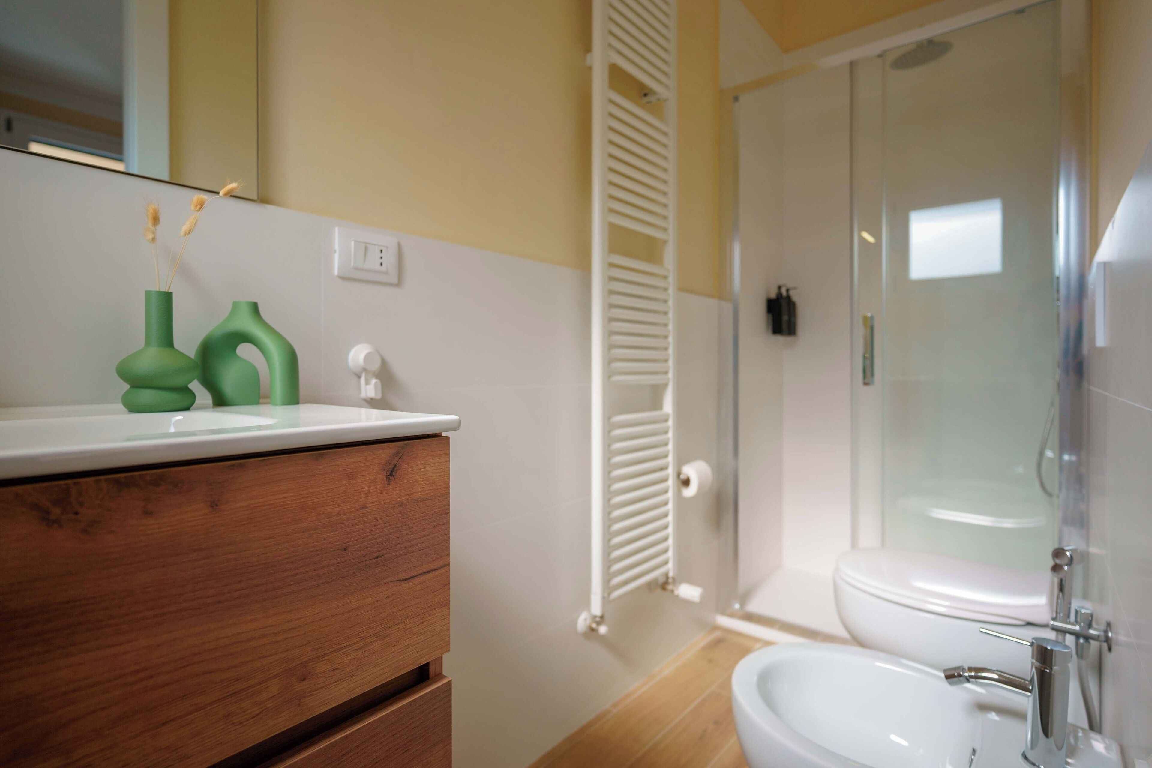 A bathroom with a wooden vanity, a white sink, a glass shower enclosure, and a toilet.