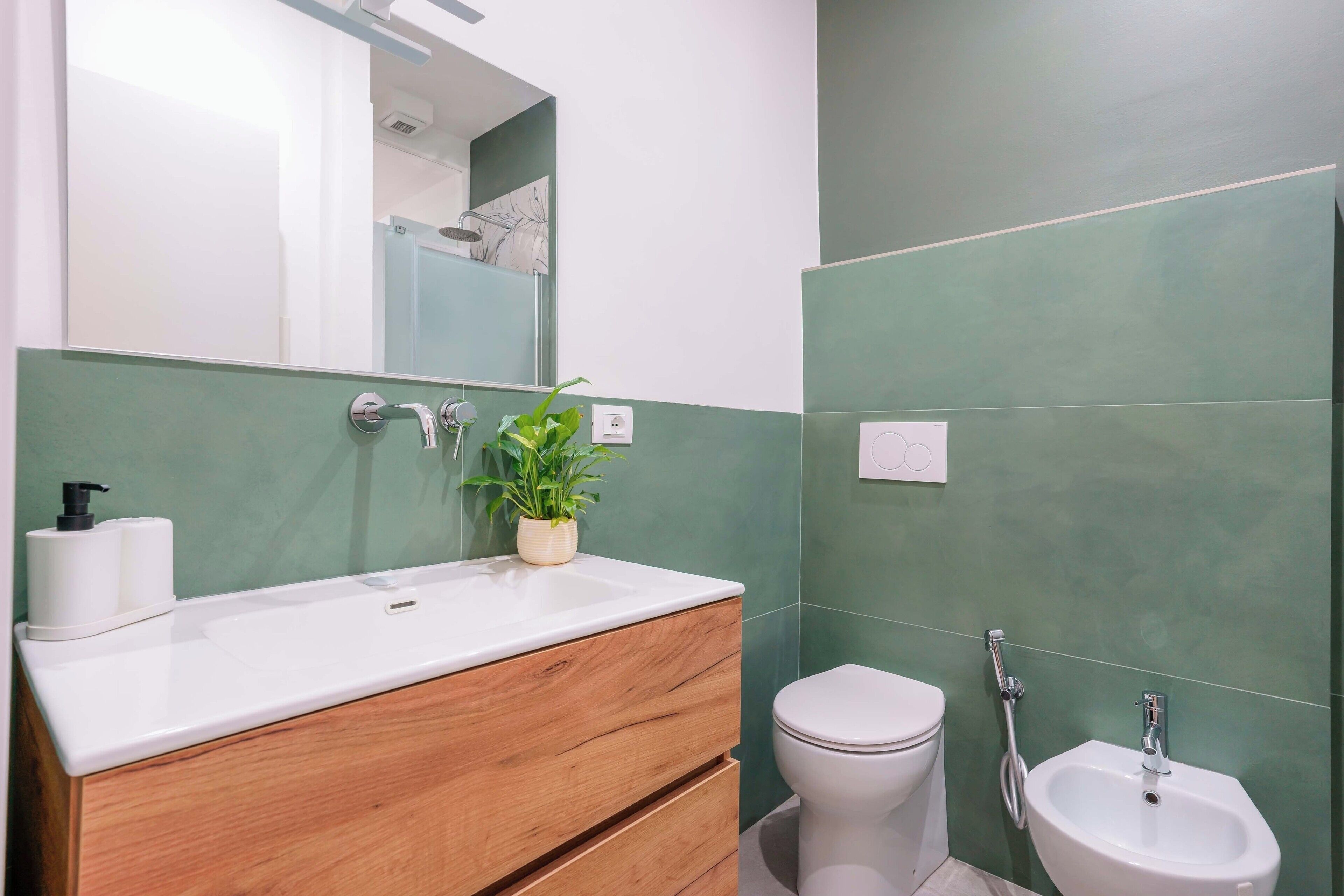 Un baño con lavamanos blanco, tocador de madera, inodoro y bidé.