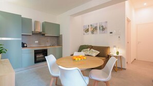 A modern kitchen with a dining area, a sofa, and a small table with a lamp. - Mascarella Apartments (Bologna)