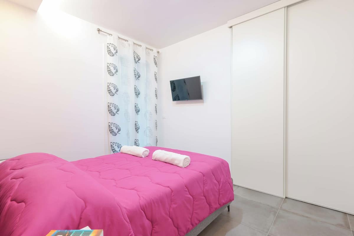 A bedroom with a bed, a TV, a curtain, and a wardrobe.