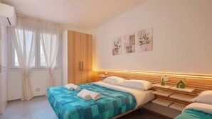 A bedroom with a bed, bedside tables, a wardrobe, and artwork on the wall. - Mascarella Apartments (Bologna)