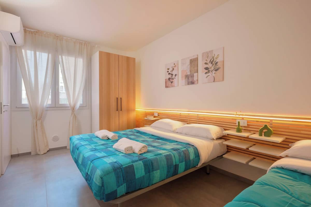 A bedroom with a bed, bedside tables, a wardrobe, and artwork on the wall.
