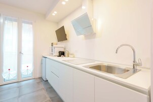 A modern kitchen with a built-in sink, a flat-screen TV, and a sliding glass door leading to an outdoor area.