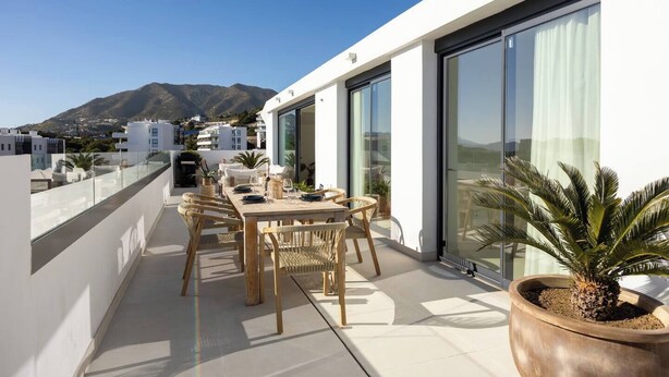 A rooftop terrace with a dining table and chairs, a potted plant, and a view of a mountain. - Panorama Luxury Penthouse in Higueron (Fuengirola)