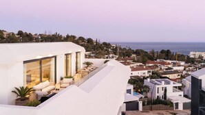 A modern building with a rooftop terrace featuring outdoor seating and a view of the sea. - Panorama Luxury Penthouse in Higueron (Fuengirola)