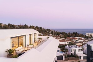 Ein modernes Gebäude mit Dachterrasse, Außenbestuhlung und Blick auf das Meer.