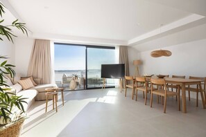 Een moderne woonkamer met een bank, eettafel, stoelen, een flatscreen-tv en een groot raam met uitzicht.