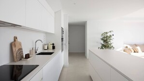 A modern kitchen with white cabinetry, a black countertop, and a plant on the island. - Panorama Luxury Penthouse in Higueron (Fuengirola)