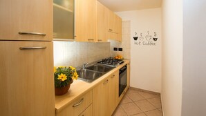 Una cocina compacta con armarios de madera, un lavamanos, una estufa y un adhesivo en la pared.