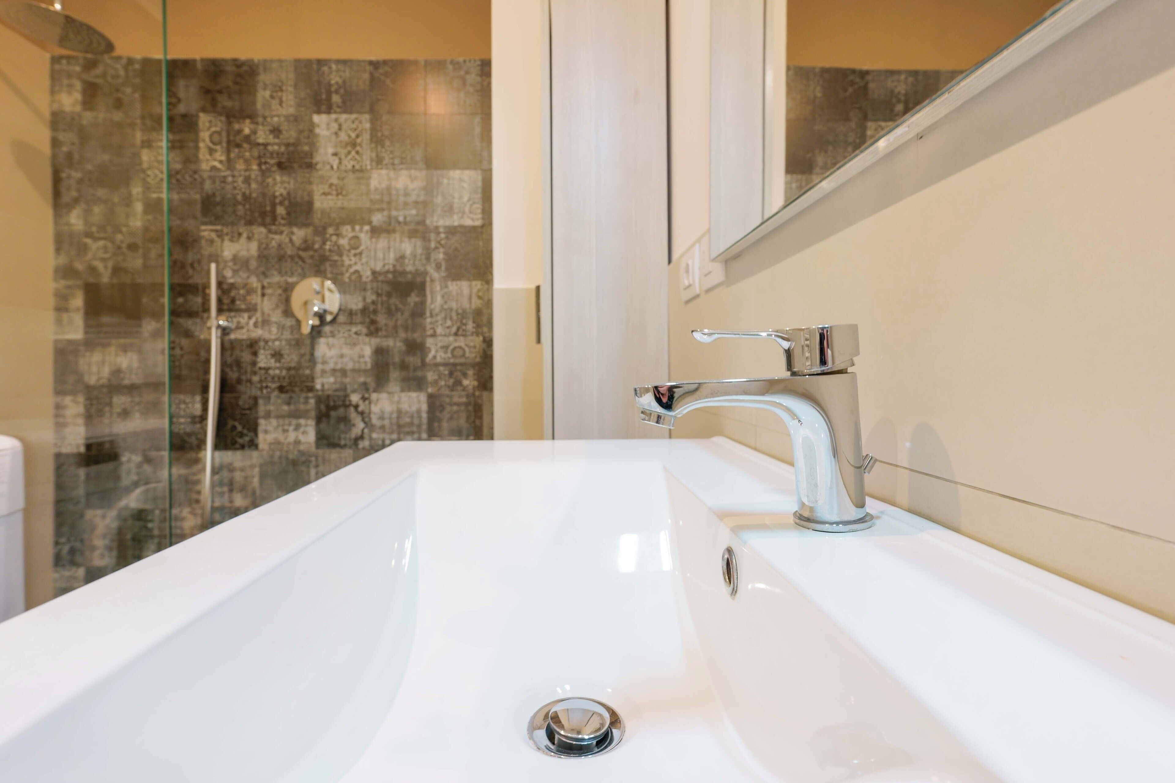 A bathroom with a white sink, a mirror, and a shower with a glass door.