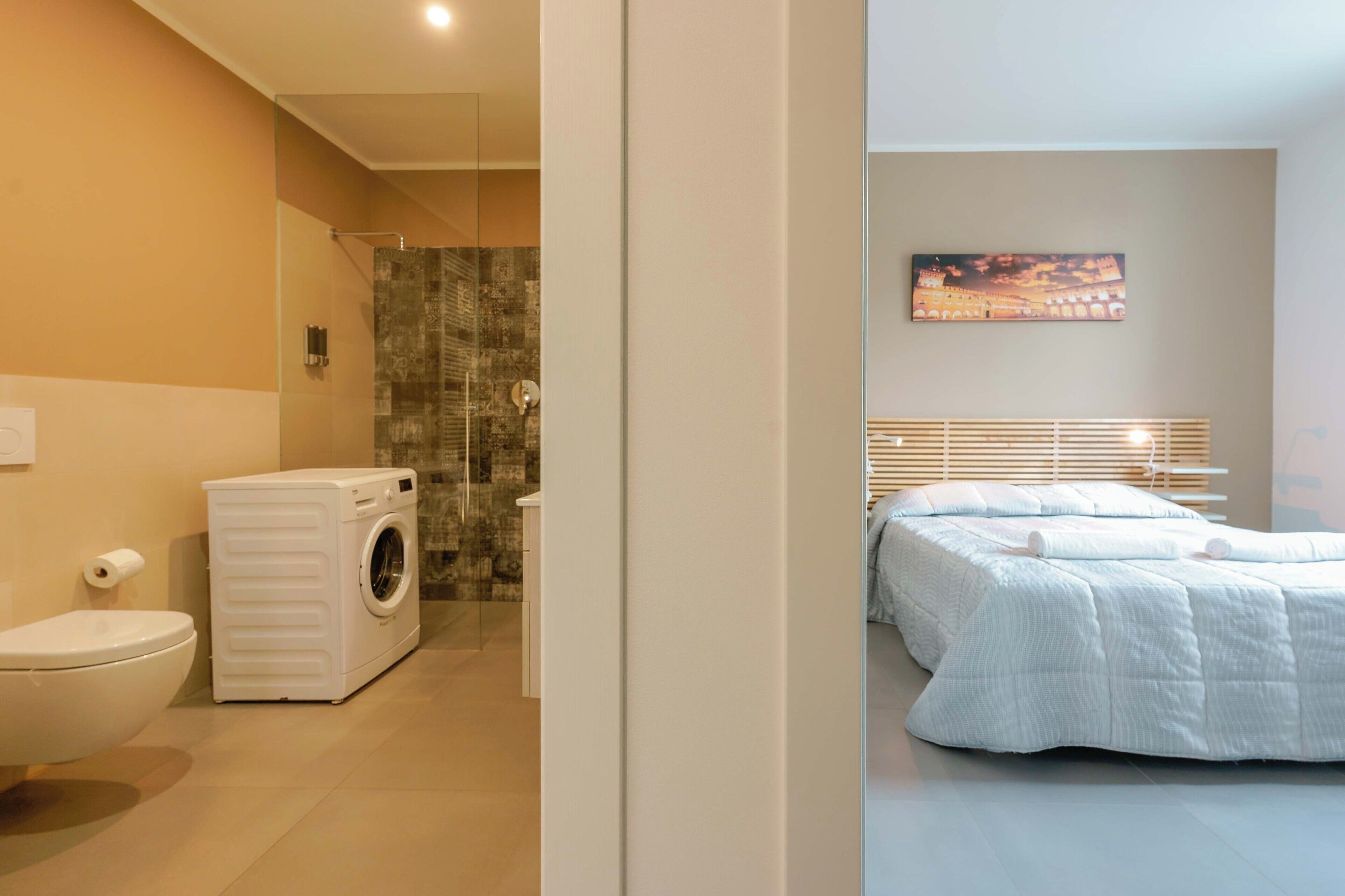 Un bagno moderno con WC, lavatrice e cabina doccia in vetro.