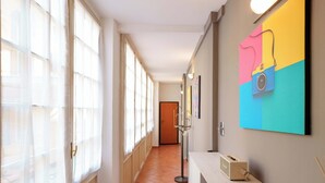 A hallway with large windows, a door at the end, and a wall-mounted light fixture. - Zamboni 58 Apartment (Bologna)