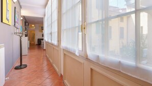 A hallway with large windows, a radiator, and a floor lamp. - Zamboni 58 Apartment (Bologna)