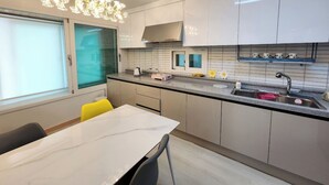 A modern kitchen with white cabinets, a marble countertop, a built-in oven, and a window with frosted glass. - Sokcho Family House Near Seorak Port, Seafood Market & Beach (Walkable) (Sokcho-si)