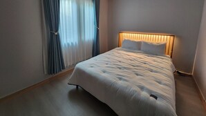 A hotel room with a bed, curtains, and a headboard with built-in lighting. - Sokcho Family House Near Seorak Port, Seafood Market & Beach (Walkable) (Sokcho-si)