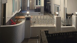 A residential building with a courtyard, featuring a staircase, a small seating area, and a gate. - Sokcho Family House Near Seorak Port, Seafood Market & Beach (Walkable) (Sokcho-si)