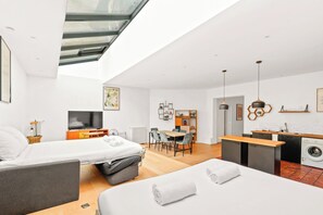 Ein modernes Hotelzimmer mit Dachfenster, Essbereich, Küche und Waschbereich.