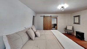 A bedroom with a large bed, a chair, a dresser, and a wardrobe. - Casa Sarita (Santa Fe)
