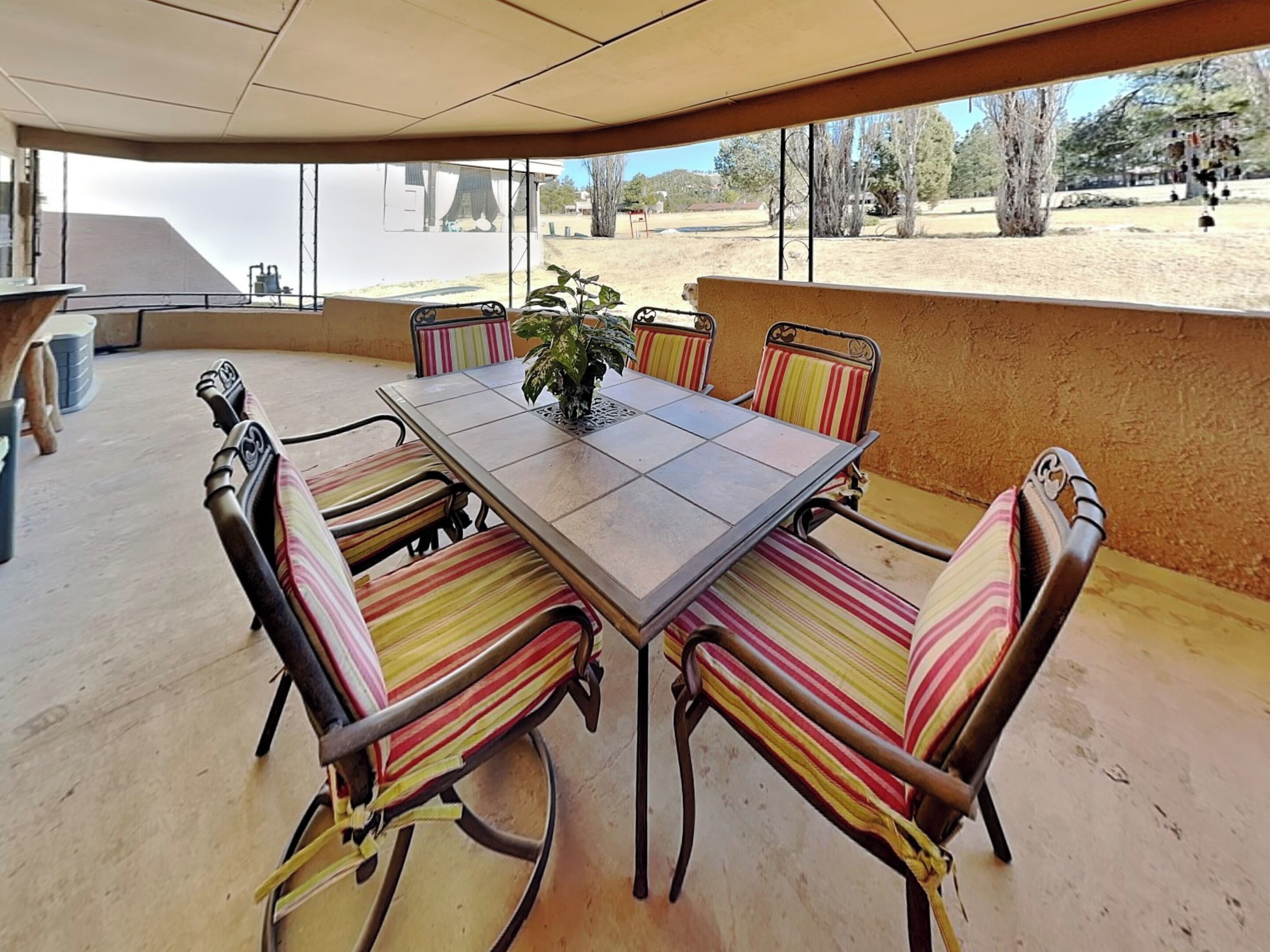 An outdoor patio with a rectangular table and six striped chairs.