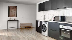 Eine kompakte Küche mit Waschmaschine, Mikrowelle und Backofen.