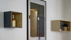 Ein Zimmer mit einer hölzernen Bank, einem gerahmten abstrakten Gemälde und zwei Regalen mit Dekoration.