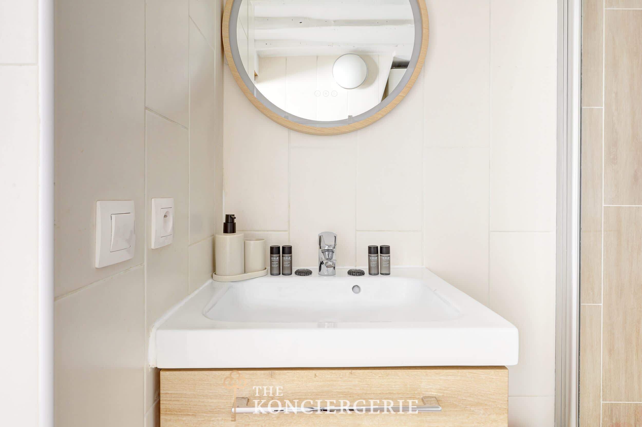 Une salle de bain avec un lavabo blanc, un miroir et un meuble en bois en dessous.