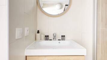 Une salle de bain avec un lavabo blanc, un miroir et un meuble en bois en dessous.