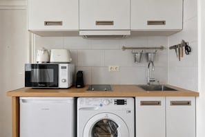 Eine kleine Küche mit Mikrowelle, Toaster, Spüle und Waschmaschine.