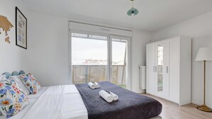 Ein modernes Schlafzimmer mit einem großen Bett, einem Balkon mit Blick und einem Kleiderschrank.
