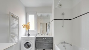 Ein modernes Badezimmer mit Waschmaschine, Waschbecken und Dusche.