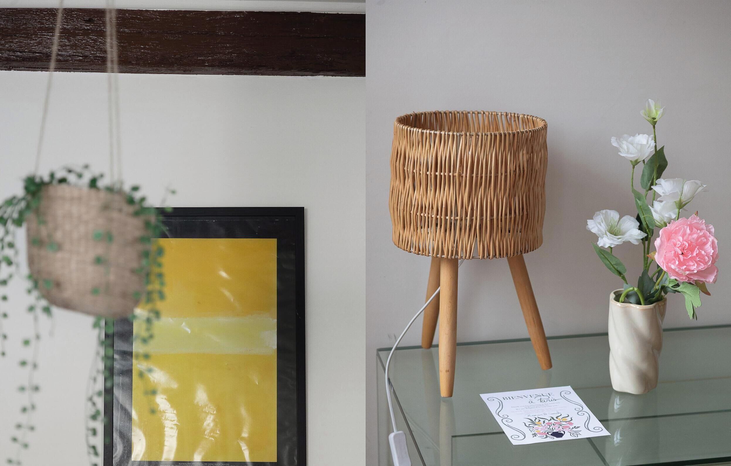 A wicker lamp on a glass table, a framed picture, and a vase with flowers.