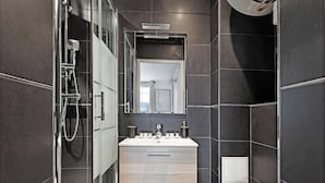 A modern bathroom with a glass-enclosed shower, a vanity with a mirror, and a sink. - Studio d'Architecte avec Cheminee - Design -4 personnes (Paris)
