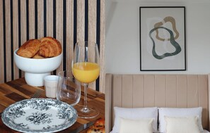 Ein Frühstückstisch mit Croissants, Orangensaft und einem weißen Teller mit floralem Dekor.