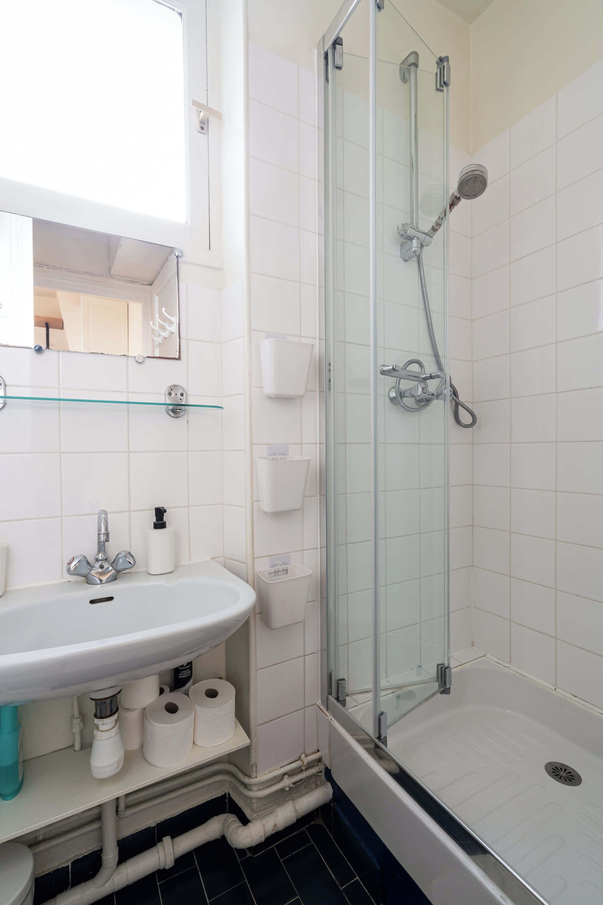 A bathroom with a glass-enclosed shower, a white sink, and a mirror above the sink.