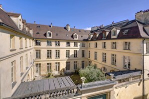 A courtyard with a central fountain, surrounded by buildings with multiple windows and a tiled roof. - Rénové 1BDR/2P – Marais / Musée Picasso (Paris)