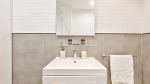 A bathroom with a white sink, a mirror above it, and a towel rack to the right. - BM Magnifique Studio avec terrasse - Arc de Triomphe (Paris)