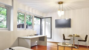 A modern room with a desk, two chairs, a TV, and large windows with a view of trees. - BM Magnifique Studio avec terrasse - Arc de Triomphe (Paris)