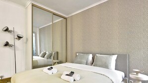 A hotel room with a large bed, a mirror, and a patterned wall. - BM Magnifique Studio avec terrasse - Arc de Triomphe (Paris)