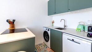 Una cocina compacta equipada con lavadora, lavaplatos y cafetera.