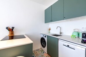 A compact kitchen with a washing machine, a sink, and a coffee maker. - Appartement 2 pièces à proximité de Gare de L'est (Paris)