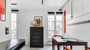 Un espace repas moderne avec une table en bois foncé dressée pour deux personnes, un meuble noir et une œuvre d’art encadrée placée au-dessus du meuble.