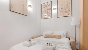 A hotel room with a bed, two wall-mounted light fixtures, and three framed artworks. - Duplex d'Exception avec climatisation - Rue Monge (Paris)