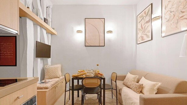 A cozy living room with a sofa, a dining table with chairs, and a kitchen area with cabinets and a refrigerator. - Duplex d'Exception avec climatisation - Rue Monge (Paris)