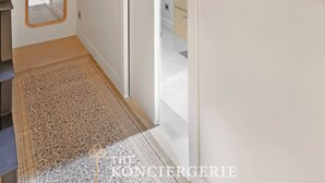 A hallway with a mirror, framed artwork, and a rug leading to a bedroom. - Duplex d'Exception avec climatisation - Rue Monge (Paris)