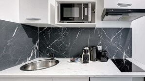 Una cocina moderna con microondas integrado, pileta de acero inoxidable y cocina de color negro.