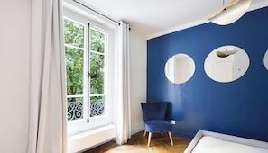 Une pièce avec une grande fenêtre, un mur bleu et une chaise.