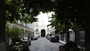 Una estrecha calle empedrada flanqueada por coches aparcados y edificios.