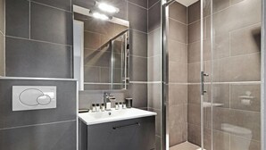 A modern bathroom with a white sink, mirror, and shower area. - Studio d'Architecte Haut de Gamme - Elegance et Confort - Paris (Paris)